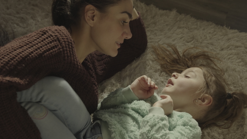 High angle close up of mother laying on floor tickling daughter . South Jordan, Utah, United States