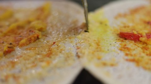Two dosas being cut, separated on pan.
South indian food