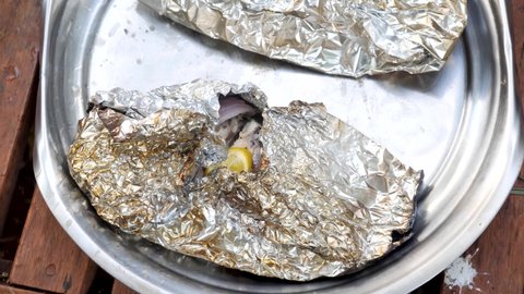 Opening up cooked tilapia in foil to see it nicely cooked.
