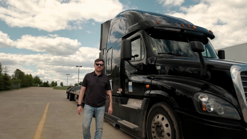 Professional Truck Driver approaches his truck and crosses his arms Behind Him Parked Long Haul Semi-Truck with Cargo Trailer Royalty-Free Stock Footage #1072823642