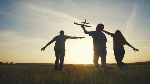happy family. boy with airplane and family running at sunset silhouette in the park. dream of becoming a pilot concept. happy family silhouette running together in the park travel. childhood dream