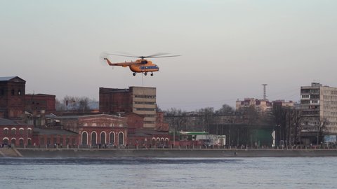Helicopter picks up bambi bucket from river. Rescue helicopter hovered. Fire helicopter low over river. Mi-8. Saint Petersburg. Neva river