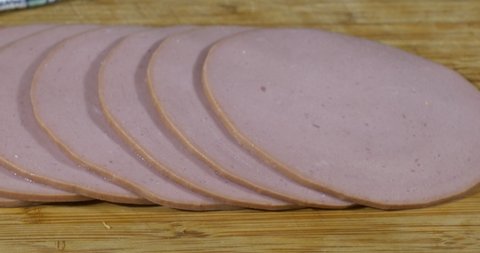 Slider shot of sliced bologna on a wooden cutting board