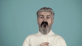 Photo booth concept. Man having fun with with fake mustache. Party props. Crazy people. - Powered by Shutterstock - Get 15% off with code: PIKWIZARD15