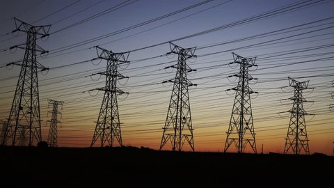 Pan of electrical power lines and pylons at dusk