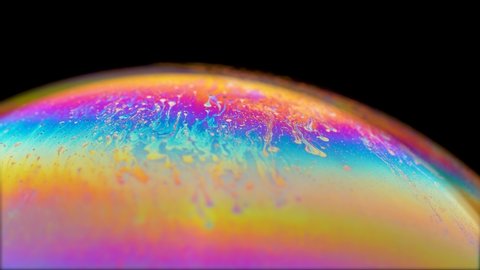 multi-colored iris texture of a soap bubble in motion hemisphere on black background