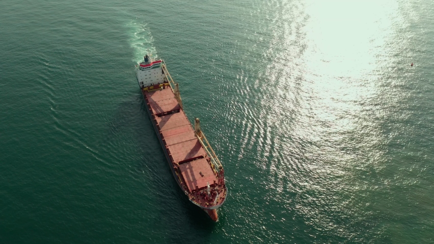Aerial view of cargo ship calling into the port for repair under the guide of tugboats.