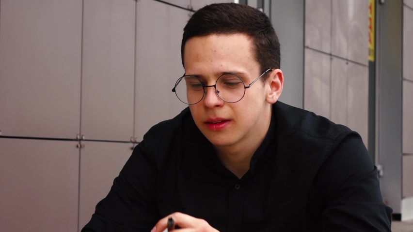 man lights a cigarette sitting on the street near the house