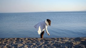 A Young Girl Playing, Skipping Stones By The Calm Blue Sea At Sunset.
