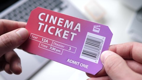 Holding a cinema ticket on the hands. Theater admission ticket with bar code.
