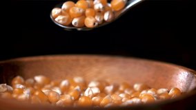 Super slow motion popcorn grains fall from spoon to plate. On a black background. Filmed on a high-speed camera at 1000 fps. High quality FullHD footage
