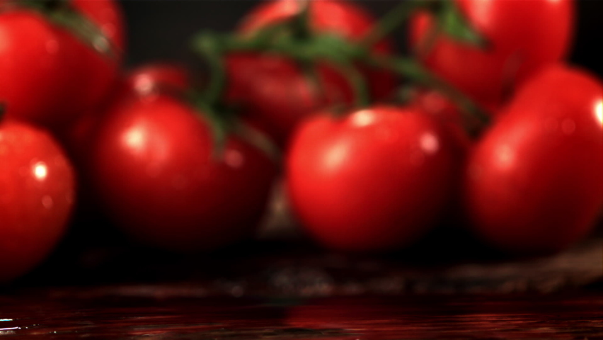 Super slow motion fresh tomato falls on the table with splashes of water. Filmed at 1000 fps.On a wooden background. | Shutterstock HD Video #1072875266