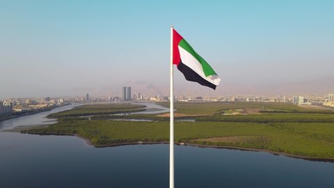 Static slow motion view of UAE national flag pole and Ras al Khaimah emirate in the northern United Arab Emirates aerial skyline landmark and skyline view above the mangroves and corniche downtown