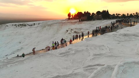 Visitors and tourist people walks touring calcium carbonate travertines.Travertine terrace formations.Sedimentary rock deposited by waters from the hot spring.Pamukkale cotton castle natural limestone