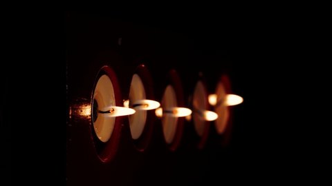 Close-up macro vertical footage of candle flames burning in the darkness.