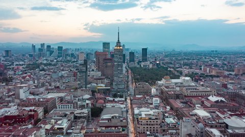 Aerial hyperlapse view of Torre Latinoamericana skyscraper in downtown Mexico City in fading evening light and Sun setting above big City, Drone View Hyper Lapse from above, Mexico City in 2021