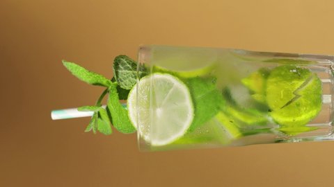 Mojito cocktail. Rotating misted glass of mojito with lime slices and mint leaves. Vertical video