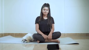 Girl teaching meditation and sitting position during online class on mobile phone - concept of online yoga live streaming on a smartphone - yoga trainer teaching via internet.