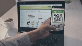 POV shot of a man sitting at the desk, holding a smartphone in the left hand, bringing it closer to a laptop screen, scanning QR code and paying with crypto wallet mobile app - Powered by Shutterstock - Get 15% off with code: PIKWIZARD15