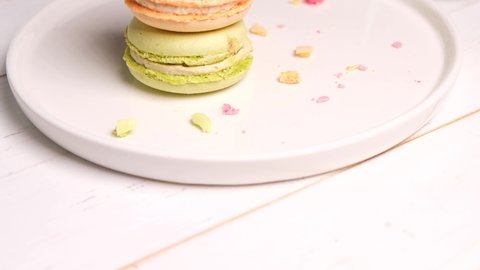 three french macaroons on a white plate composition against white background with flowers