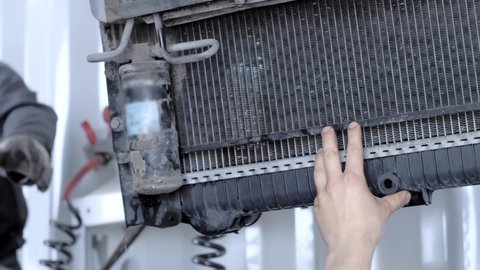 A professional mechanic installs a fan radiator on a truck during an annual maintenance service at a truck service station