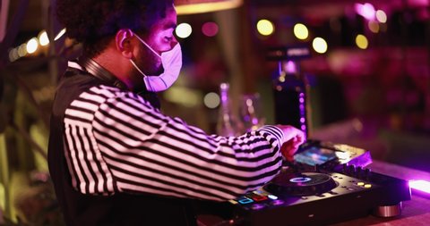 Black Dj playing music at cocktail bar outdoor while wearing face safety mask - Entertainment, social distance and party concept 