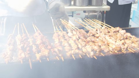Street Food Kabobs Are Being Cooked On The Hot Smoking Charcoal Grill In The Sun By The Vendor.