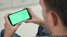 Side view on adult man looking at smartphone with chroma key screen. Caucasian man is looking at smartphone with chroma key screen.