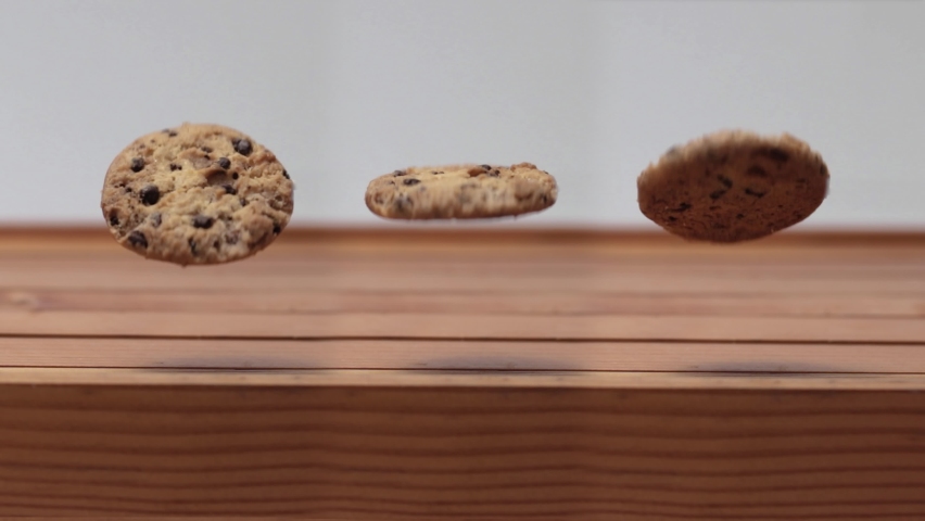 Three Chocolate Chip Cookie Spinning and Rolling in the Air above Wooden Table, 4K Royalty-Free Stock Footage #1072921832