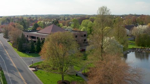 Aerial establishing shot of business office building set among blooming trees in suburban park in United States, USA.