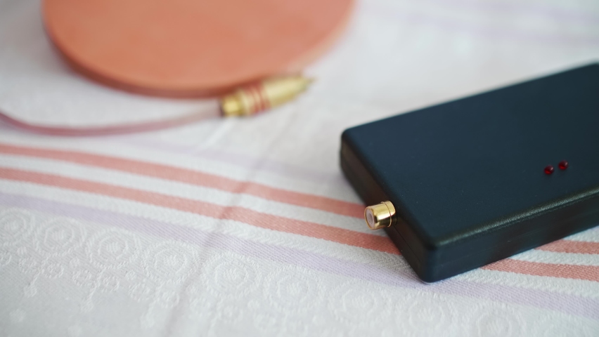 Focused view of woman hands putting connector into socket of power bank. Special coil as tool to cure diseases. Piece of alternative medecine.