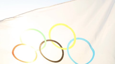 The Olympic flag flutters in the wind against the background of the sky and the sun in close-up. The symbol of the Olympic Sports Games, fans. Kaluga, Russia, May 20, 2021
