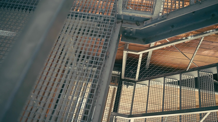 Young woman runner, jump on up the stairs on modern Iron structures. Female model in sportswear exercising outdoors. Health concept, take care of yourself and your balance. Running outdoor in sun.