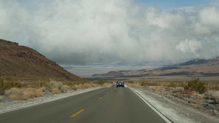 Road trip to Death Valley, driving auto in California, USA. Hitchhiking traveling in America. Highway, mountains and dry desert, arid climate wilderness. Passenger POV from car. Journey to Nevada.