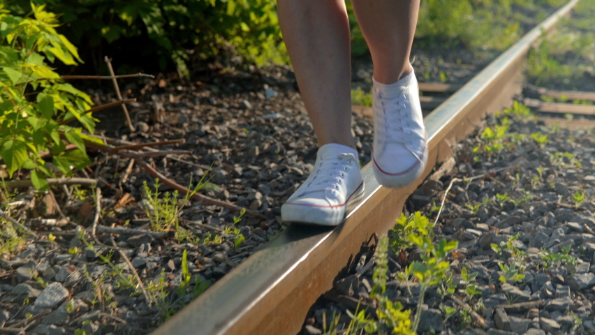 Close-up shot of a girl walking on the rails. Walk along the railroad tracks. Old train track 4k