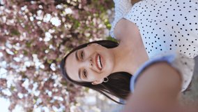 Vertical video of smiling woman having video call on smartphone in city, friendly woman waving hand at camera, pretty woman video chatting at phone, stylish blogger making video on phone outdoor - Powered by Shutterstock - Get 15% off with code: PIKWIZARD15