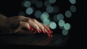 Accelerated video of female hands is typing on a laptop at night. Blurred lights on the background. Quick motion. Timelapse
