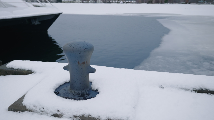 Mooring Bollard On Snowy Quay With Ice On Water In Bakcground At Wintertime. - static