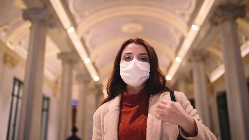 Beautiful girl in fashionable clothes holds and wears disposable mask.New normal lifestyle concept.