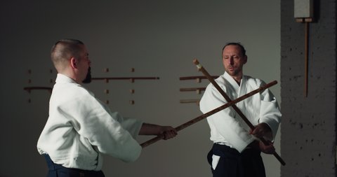 Cinematic shot of two fighters practicing with wooden sword Aikido training in modern Japanese martial arts school. Concept of sports and recreation, philosophy, defense, religious beliefs.