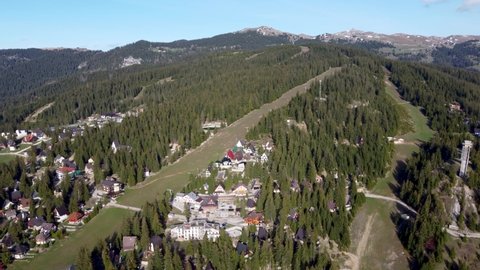 Aerial drone view of ski resort and apartments in the woods. Mountain. Slopes with green grass in early spring. Vlasic, Bosnia and Herzegovina.