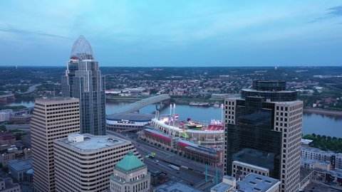 Cincinnati, Ohio, USA - May 18 2021: 4K Drone aerial footage of downtown Cincinnati, Ohio. Drone pedestals down and then circles an American flag waving in the wind at the top of a skyscraper. 