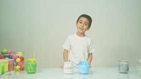 A boy was joyfully mixing a new color.
Boy mixing colors Learning materials in school, Montessori method that children manage.
high quality 4K video studio shot. colorful background.
