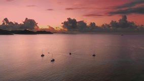 Pink-orange sunset on La Digue island, Seychelles, beautiful sunset overlooking the ocean and boats floating on the water.