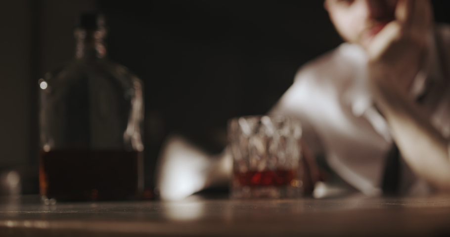 The man pushes the glass of whiskey away from him with a confident movement of his hand. With this gesture, he indicates that he will no longer drink alcohol.  Royalty-Free Stock Footage #1072963607
