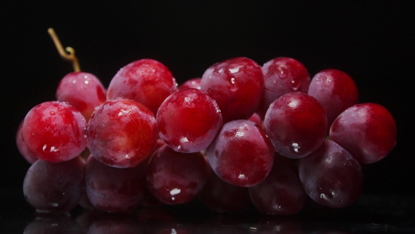 Wet fresh grapes close up, rotating on black background. Eco product for healthy food.