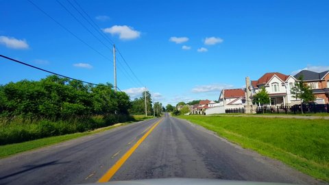 Driving Residential City Road With Lush Trees During Summer Day.  Driver Point of View POV Along Beautiful Sunny Suburban Street.