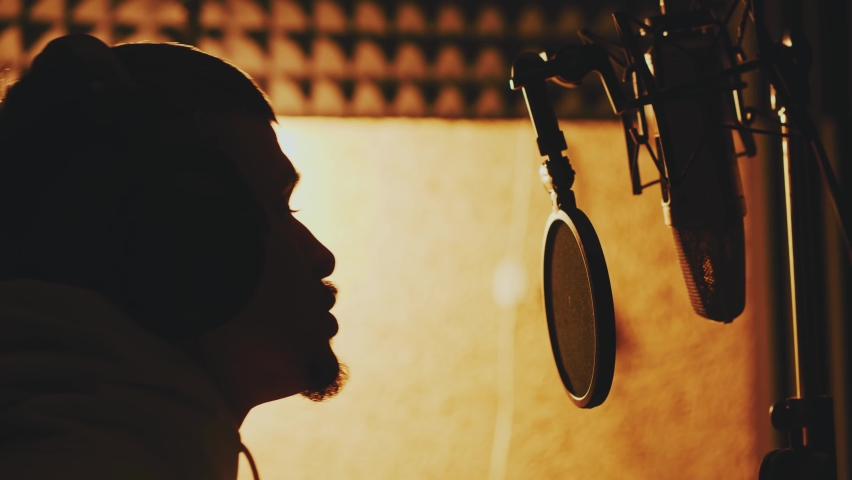 Hip hop artist singing rap song and shaking head with rhythm. Young male recording vocals and practicing inside modern music studio. Royalty-Free Stock Footage #1072966340