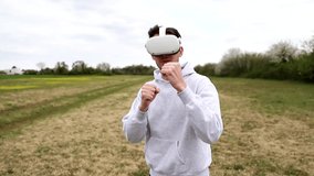 A boy in an open-air meadow plays a boxing game using virtual reality headsets