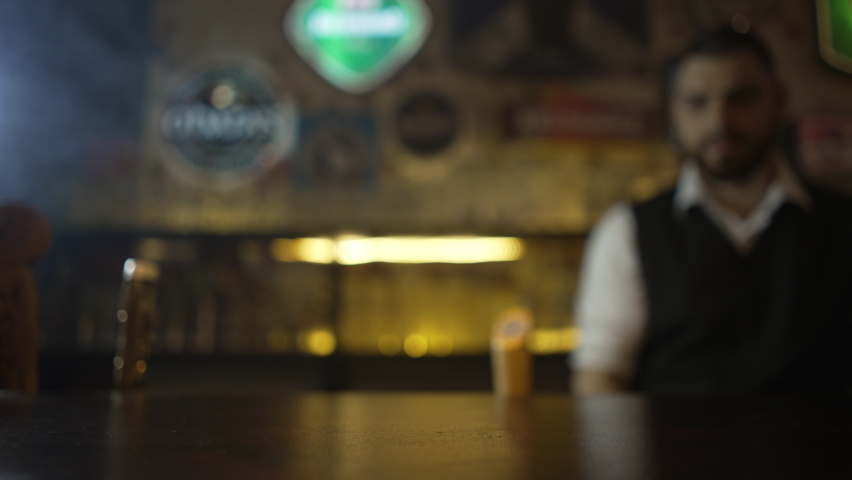 The bartender puts a glass of unfiltered beer on the bar. Slow motion video of the bartender. Beer pub party. Royalty-Free Stock Footage #1072969664